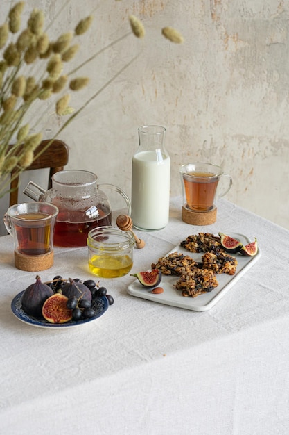 Café da manhã com chá e mel, leite e biscoitos na toalha de linhoStill Life Copy space Banner