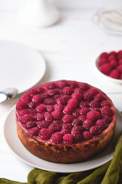 Foto café da manhã com cheesecake de framboesa. sobremesa um prato sobre uma mesa de madeira branca.