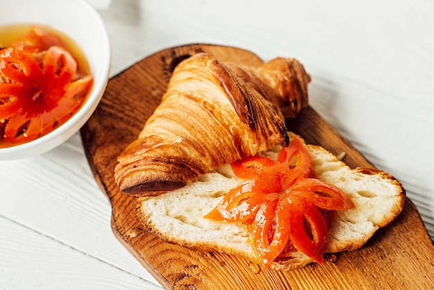 Café da manhã com croissant fresco e geléia de tangerina, escultura de frutas. Café da manhã saudável.