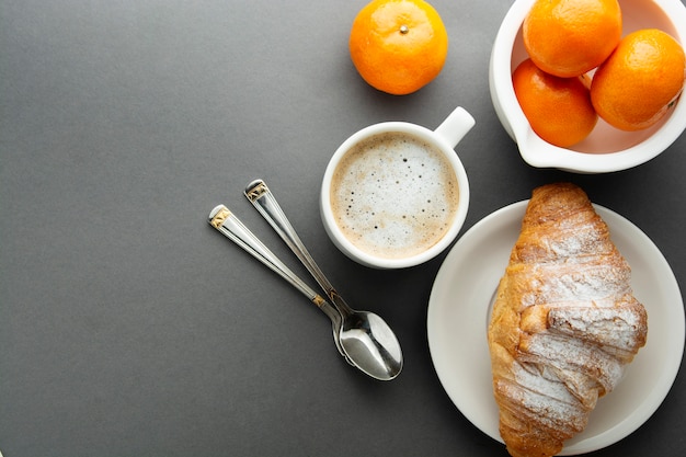 Café da manhã com croissant, frutas cítricas francesas, pastelaria, uma xícara de café ou café com leite. Cafeína aditada.