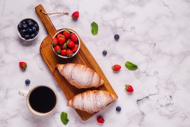 Café da manhã com croissants e frutas frescas, vista de cima.