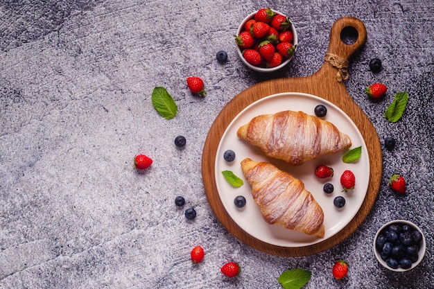 Café da manhã com croissants e vista superior de frutas frescas