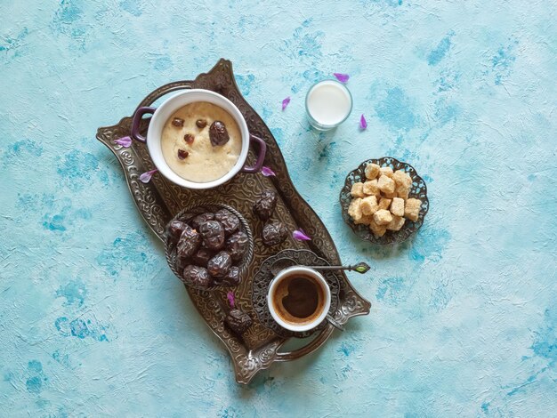 Café da manhã com datas, café e mingau saudável na mesa azul.