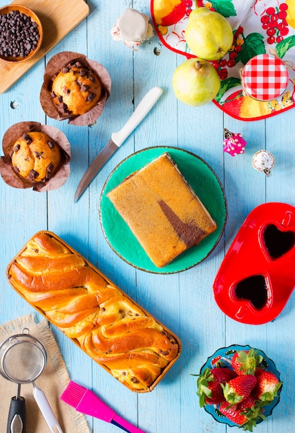 Café da manhã com diferentes bolos e frutas em uma mesa de madeira