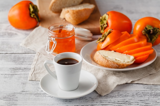 Café da manhã com geléia de frutas caqui e café na mesa de madeira