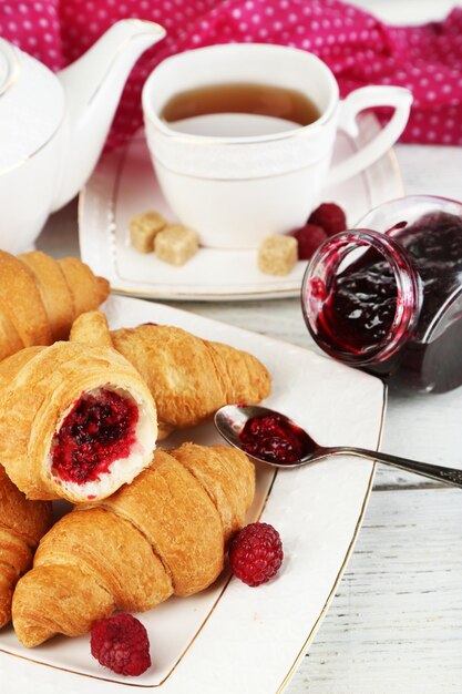 Café da manhã com geléia de suco de maçã de chá e croissants frescos na mesa de madeira no fundo brilhante