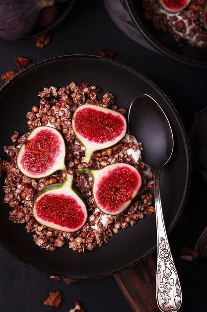 Café da manhã com granola e figos. Pratos pretos com um pequeno-almoço fresco e saudável. Comida saudável