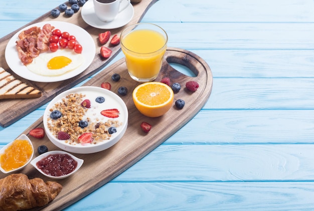 Café da manhã com iogurte ovos bagas suco de croissant e geleia