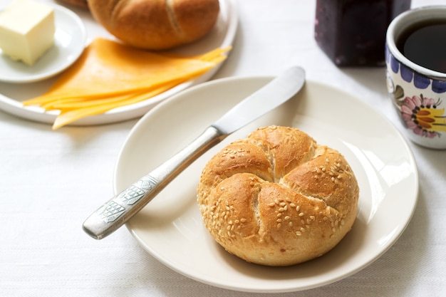 Café da manhã com pãezinhos kaiser, geléia de groselha, manteiga e queijo e chá.