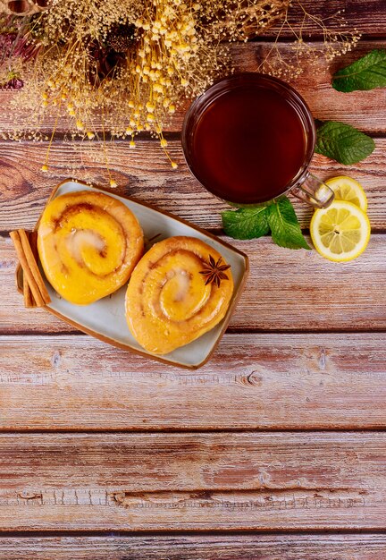 Café da manhã com rolos de canela vitrificada e xícara de chá com limão e hortelã