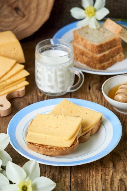 Café da manhã com sanduíche de queijo, leite e mel em uma mesa de madeira