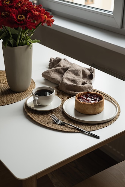 Foto café da manhã com torta de café e baga composição estética de natureza morta com flores de café de sobremesa buquê de linho cobertor garfo na mesa branca