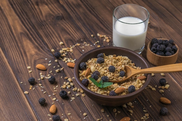 Café da manhã com um copo de granola de leite e frutas em uma mesa de madeira