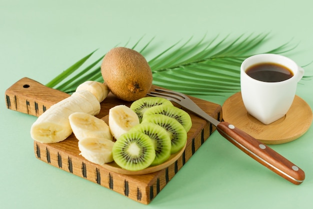 Café da manhã com xícara de café e frutas. fatias frescas de kiwi e banana. Conceito de pequeno-almoço saudável.