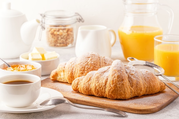 Café da manhã continental com croissants frescos, suco de laranja e café, foco seletivo.