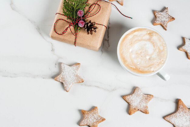 Café da manhã de Natal, caneca de café com biscoitos de gengibre estrela, com presente de Natal ou presente, na mesa de madeira branca vista superior copyspace