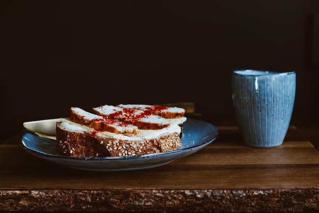 Café da manhã de nutrição saudável com café expresso e sanduíche com queijo e peito de peru em um prato azul servido em uma bandeja de madeira rústica