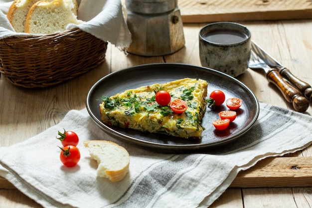 Café da manhã de omelete com legumes, ervas e queijo, servido com pão e café.