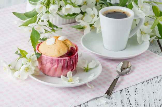 Café da manhã de primavera. bolinho e xícara de chá em uma mesa, o ramo florescendo nas pequenas flores brancas