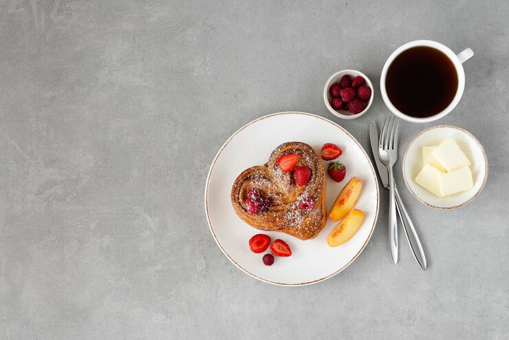 Foto café da manhã do dia dos namorados em fundo cinza pão com manteiga e frutas em um prato branco