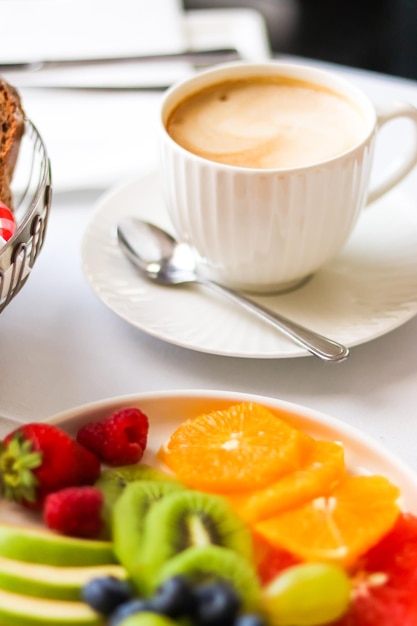 Café da manhã e café de luxo com prato de leite e frutas na mesa servida para hospitalidade e gastronomia