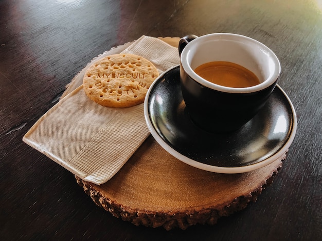 Café da manhã em copo preto e biscoitos na tábua de madeira