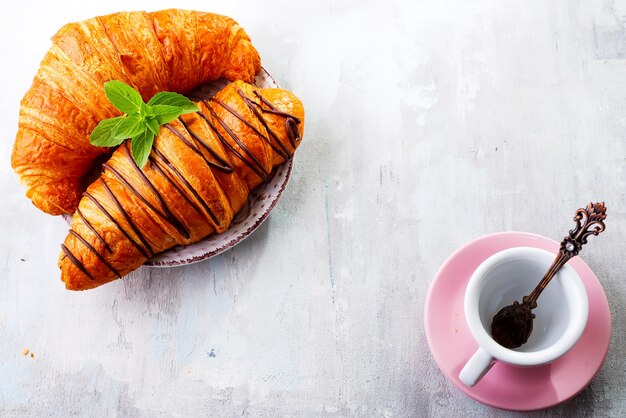 Café da manhã em uma superfície de madeira branca com croissants e café