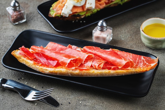 Café da manhã espanhol tradicional Tostada com diferentes coberturas em um fundo escuro