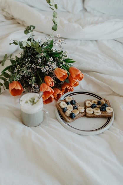 Café da manhã estético romântico na cama com flores de tulipa um espaço de cópia matcha latte e sem pessoas