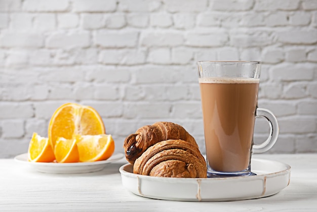 Café da manhã europeu Café Mocha com croissant e laranja em uma mesa de madeira