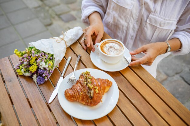 Café da manhã francês feito de um croissant e uma xícara de café no terraço de verão do café