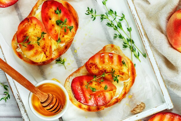 Café da manhã gourmet de verão - sanduíches (torradas de pão, bruschetta) com pêssegos grelhados, cream cheese