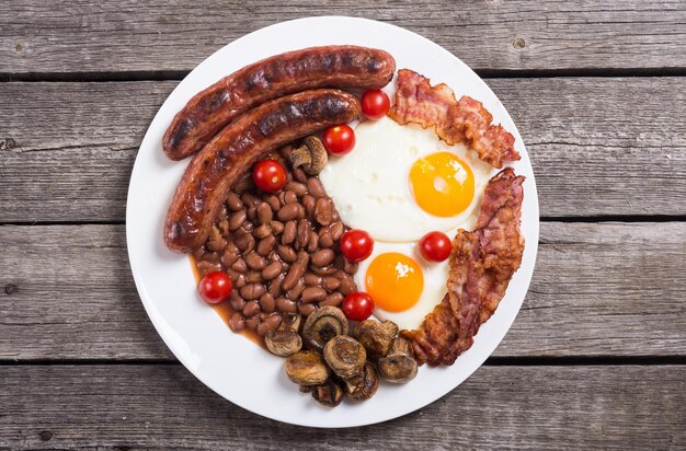 Café da manhã inglês com bacon, salsichas, ovos, tomates, cogumelos e feijões.