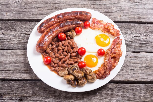 Café da manhã inglês com bacon, salsichas, ovos, tomates, cogumelos e feijões.