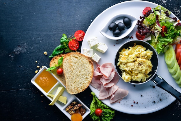 Café da manhã inglês Ovos azeitonas legumes frescos nozes frutas secas e mel Vista superior Espaço livre para texto Em um fundo de madeira