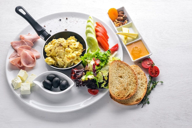 Café da manhã inglês Ovos azeitonas legumes frescos nozes frutas secas e mel Vista superior Espaço livre para texto Em um fundo de madeira