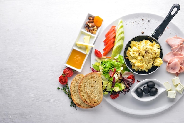 Café da manhã inglês Ovos azeitonas legumes frescos nozes frutas secas e mel Vista superior Espaço livre para texto Em um fundo de madeira