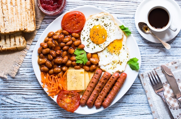 Café da manhã inglês. Ovos fritos salsichas feijão pão torradas tomate queijo em um fundo de madeira