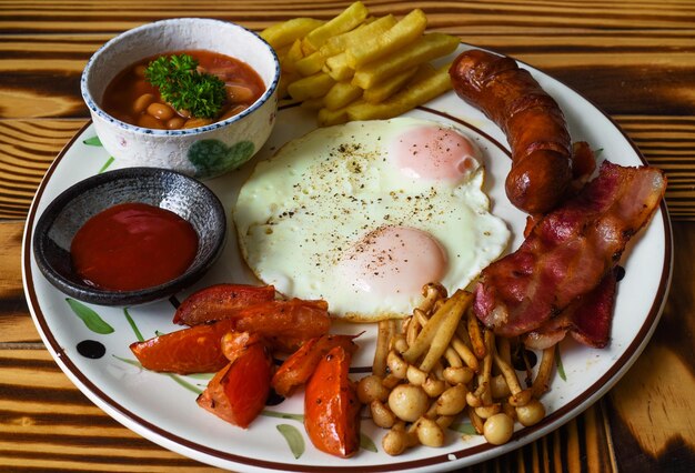 Café da manhã inglês saudável com ovos fritos salsichas bacon batatas fritas feijão e tomate fecham