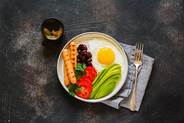 Café da manhã inglês tradicional com ovos fritos, bacon, feijão, torradas e tomates em concreto cinza