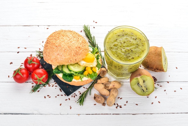 Café da manhã Kiwi e queijo hambúrguer com ovos de codorna e legumes Em um fundo de madeira Vista superior Copiar espaço