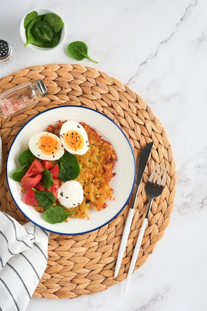 Café da manhã Latkes de batatas com creme de leite salada de espinafre tomate e ovos cozidos no fundo da mesa de mármore leve Comida deliciosa no café da manhã Vista superior