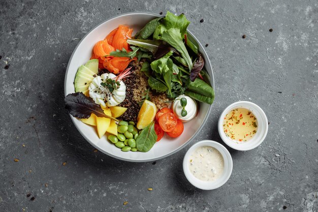 Café da manhã leve e saudável fresco, almoço de negócios. café da manhã com ovo escalfado, trigo sarraceno, peixe vermelho, salada fresca, pepino e tomate cereja, conceito de almoço de negócios.