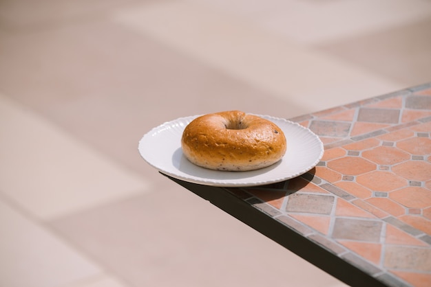 Café da manhã manhã ensolarado clima quente com donut na chapa branca no fundo da mesa. bom humor visualização horizontal