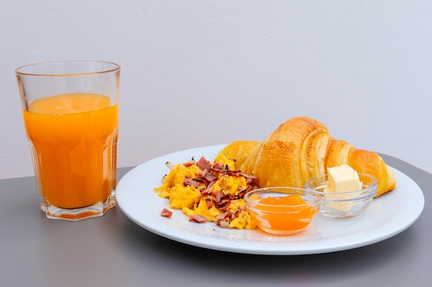 Café da manhã mediterrâneo português com croissant de ovos mexidos com bacon manteiga geléia suco de laranja