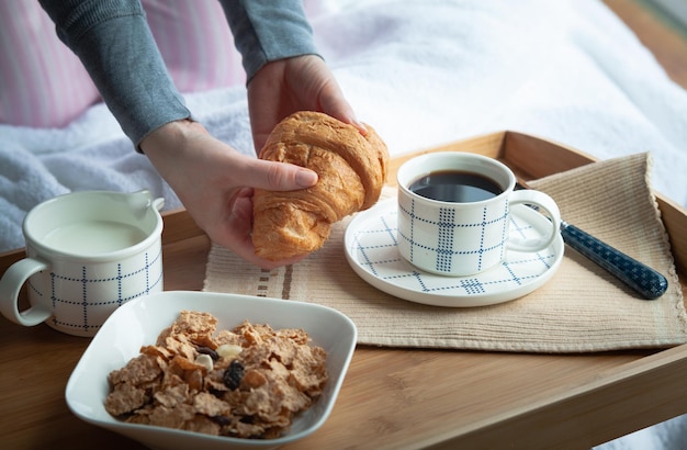 Café da manhã na cama com croissant e café em um quarto de hotel aconchegante. Delicioso começo do dia