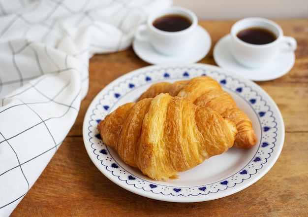 Café da manhã na cama croissants frescos e uma xícara de café em uma bandeja de madeira Bom dia