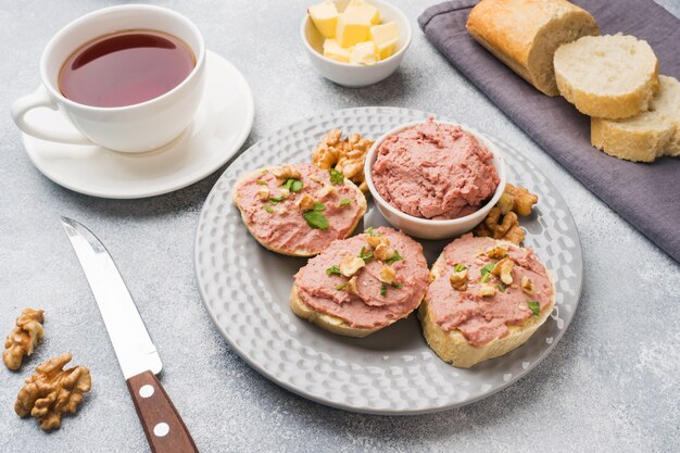 Café da manhã na mesa. sanduíches de patê de frango e manteiga. copo de chá