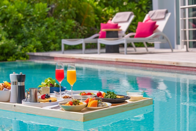 Café da manhã na piscina, café da manhã flutuante em resort tropical de luxo. Férias de viagem de mesa de comida