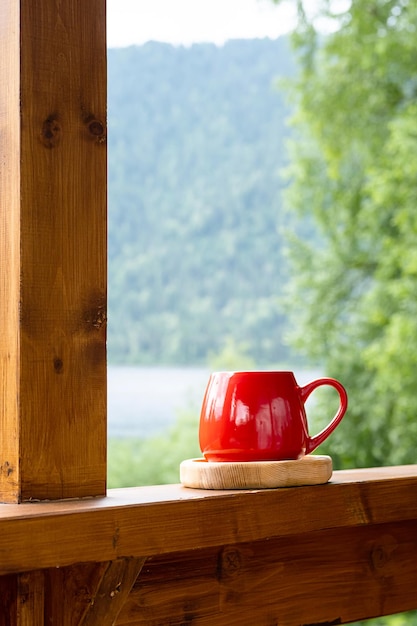 Café da manhã no jardim Caneca vermelha na placa de madeira contra a natureza turva